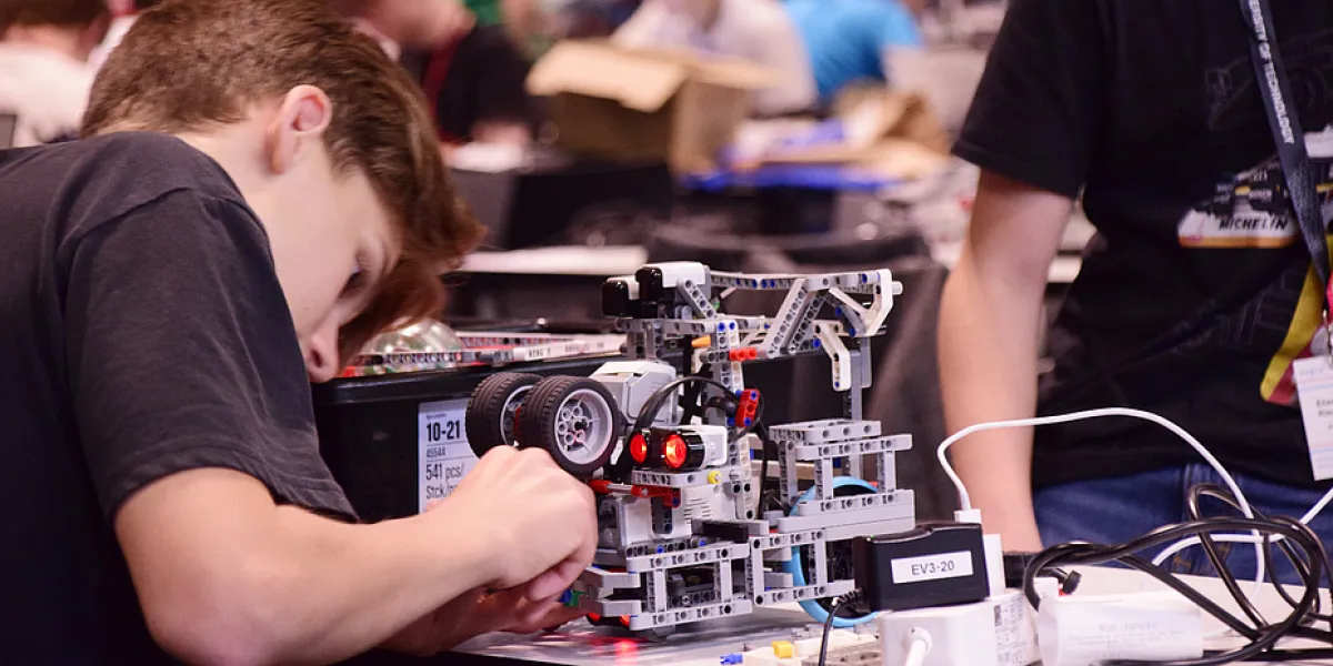 Ein Bub arbeitet gerade an einem Roboter, der aus Lego konstruiert wurde.
