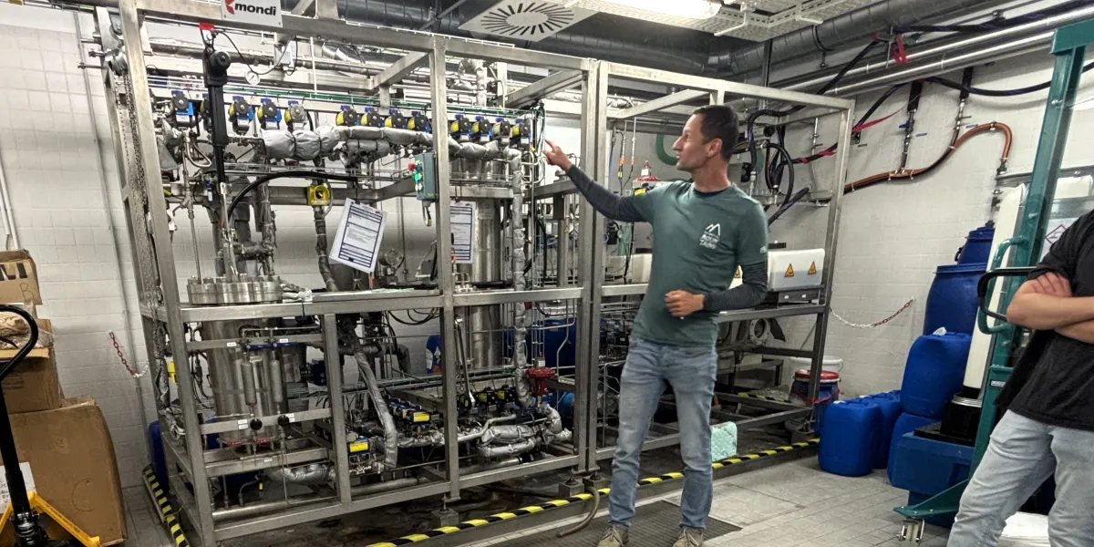Im Labor der Verfahrenstechnik: Ein Lehrender steht vor einer gro&szlig;en Maschine mit vielen verwundenen Rohren.