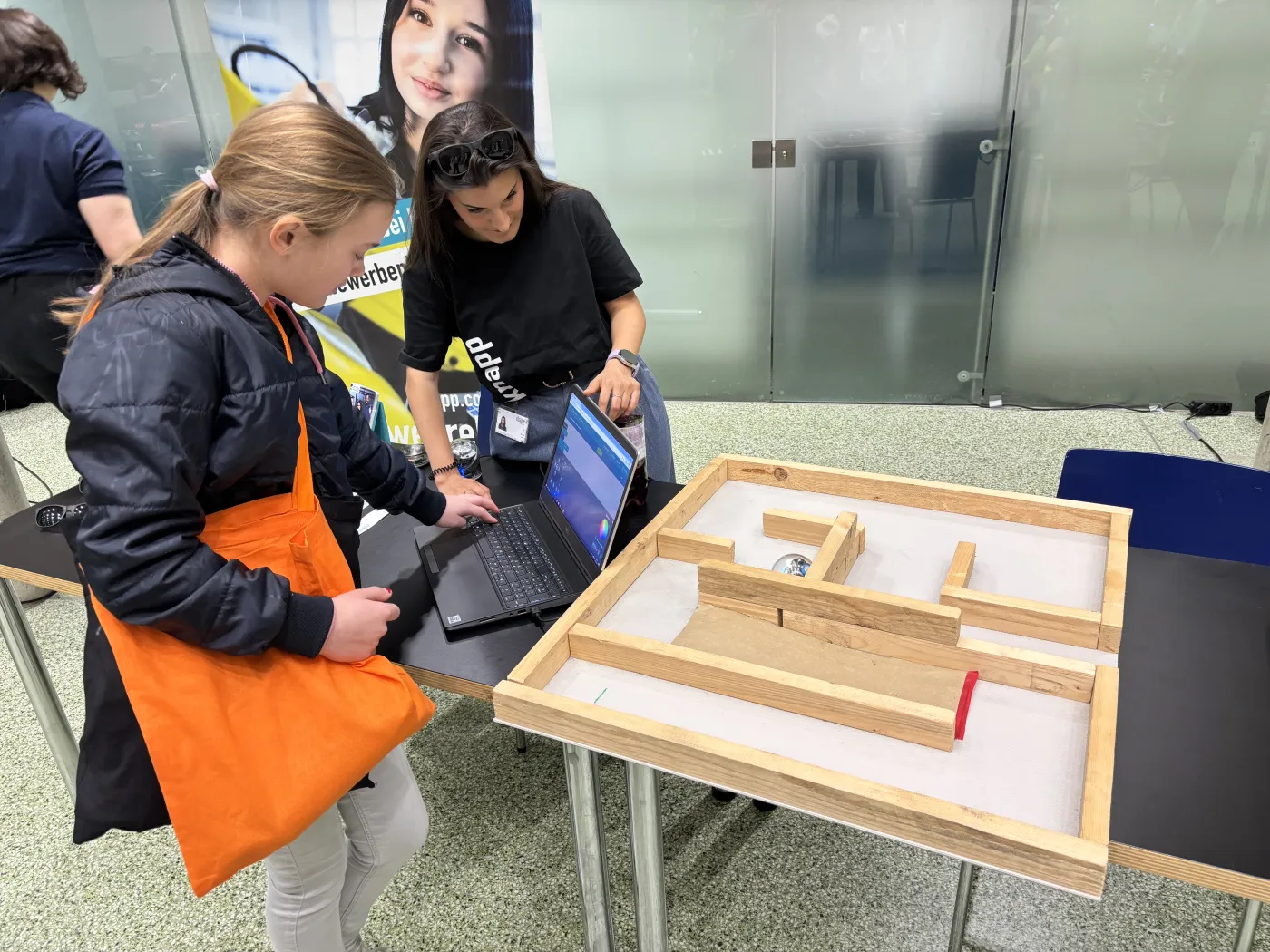 Roboter steuern! Ein M&auml;dchen lenkt einen kugelf&ouml;rmigen Roboter durch ein Labyrinth.