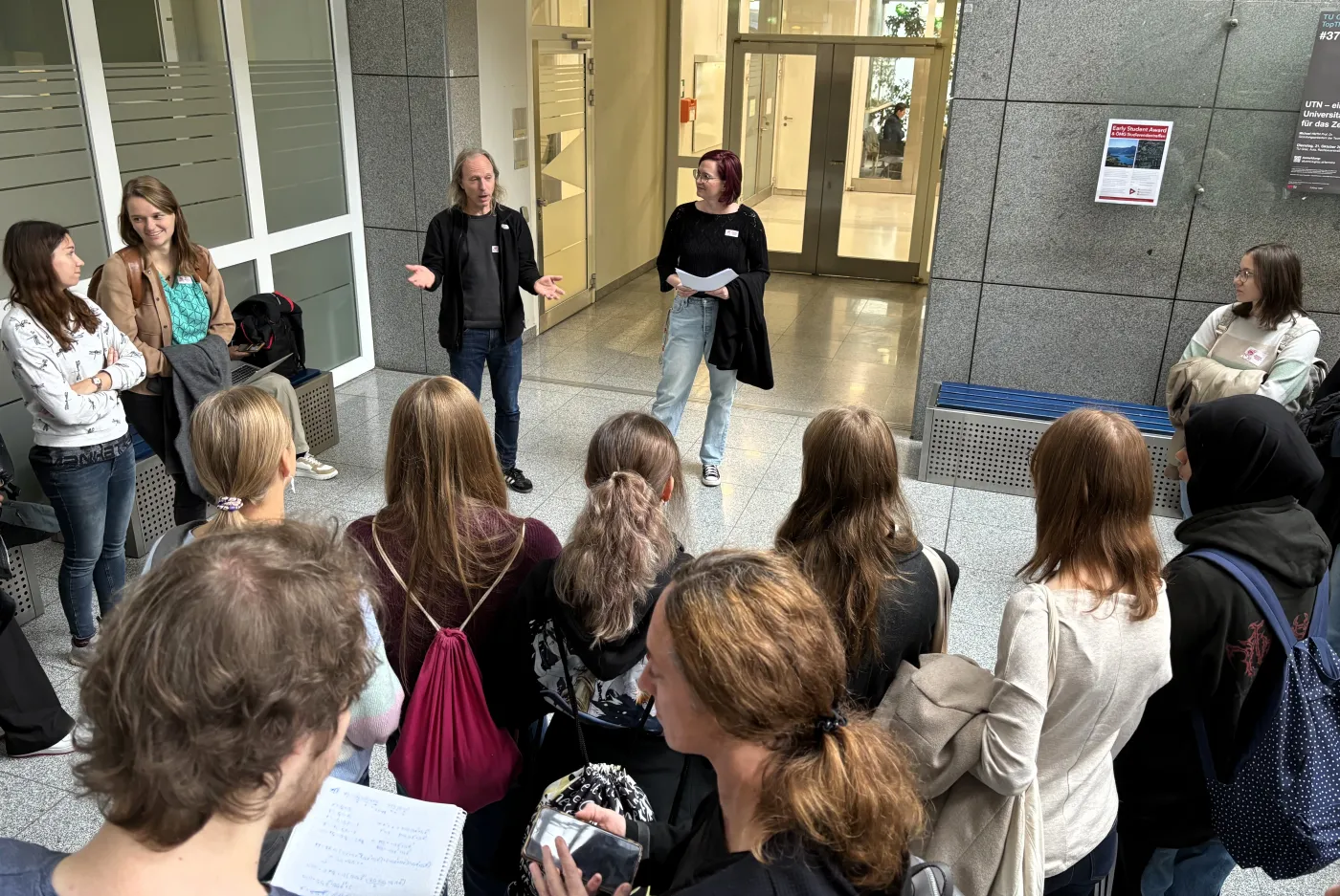 Einleitung zur Geod&auml;sie: eine Gruppe von Sch&uuml;ler*innen versammelt sich in einem Kreis vor zwei Lehrenden.