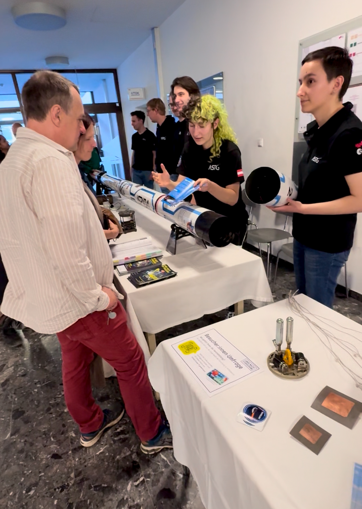 Der Stand des Aerospace Teams: Ihre Rakete liegt geöffnet auf dem Tisch. Studierende erklären, wie sie funktioniert.