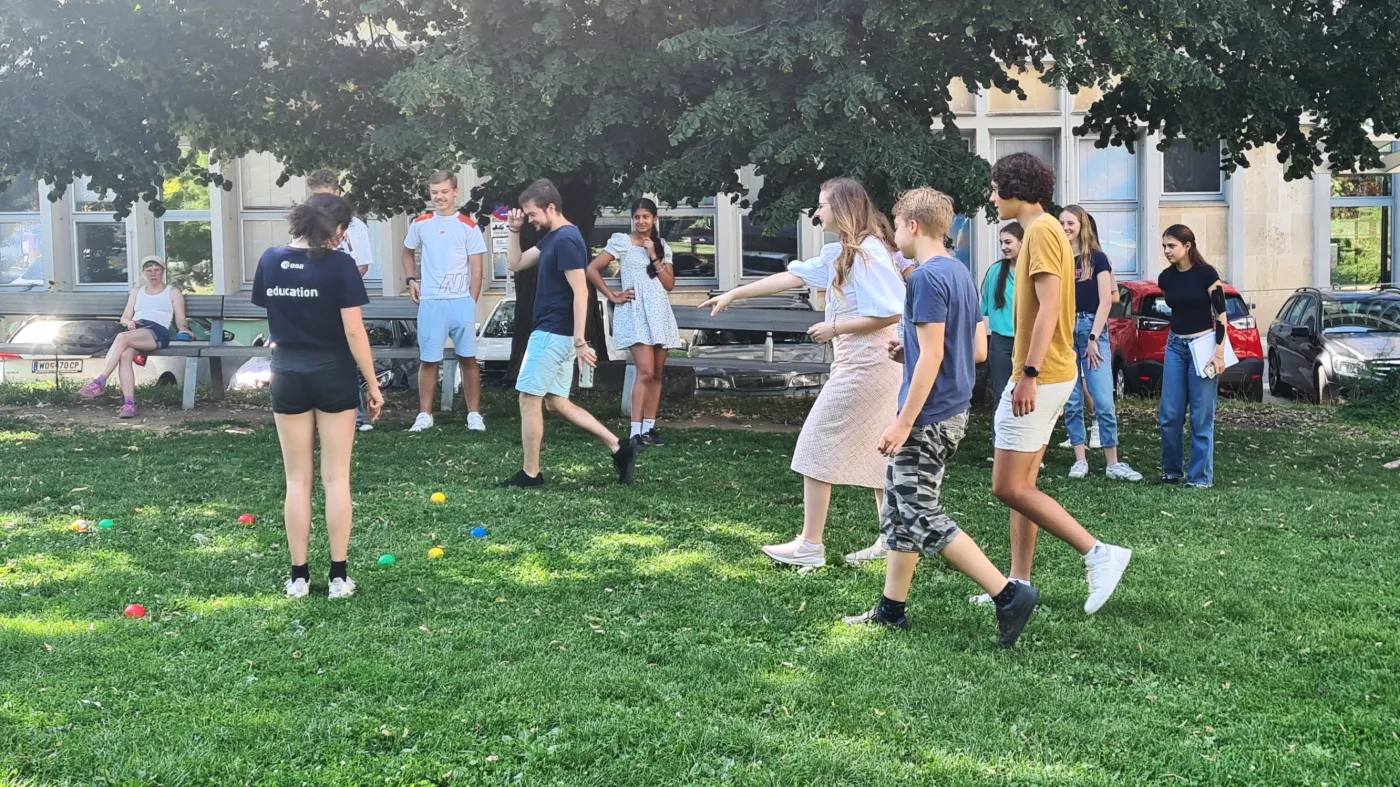 Ein Ausschnitt vom Bocciaspiel. Einige Spieler*innen zeigen auf die B&auml;lle, die am saftigen Rasen liegen.