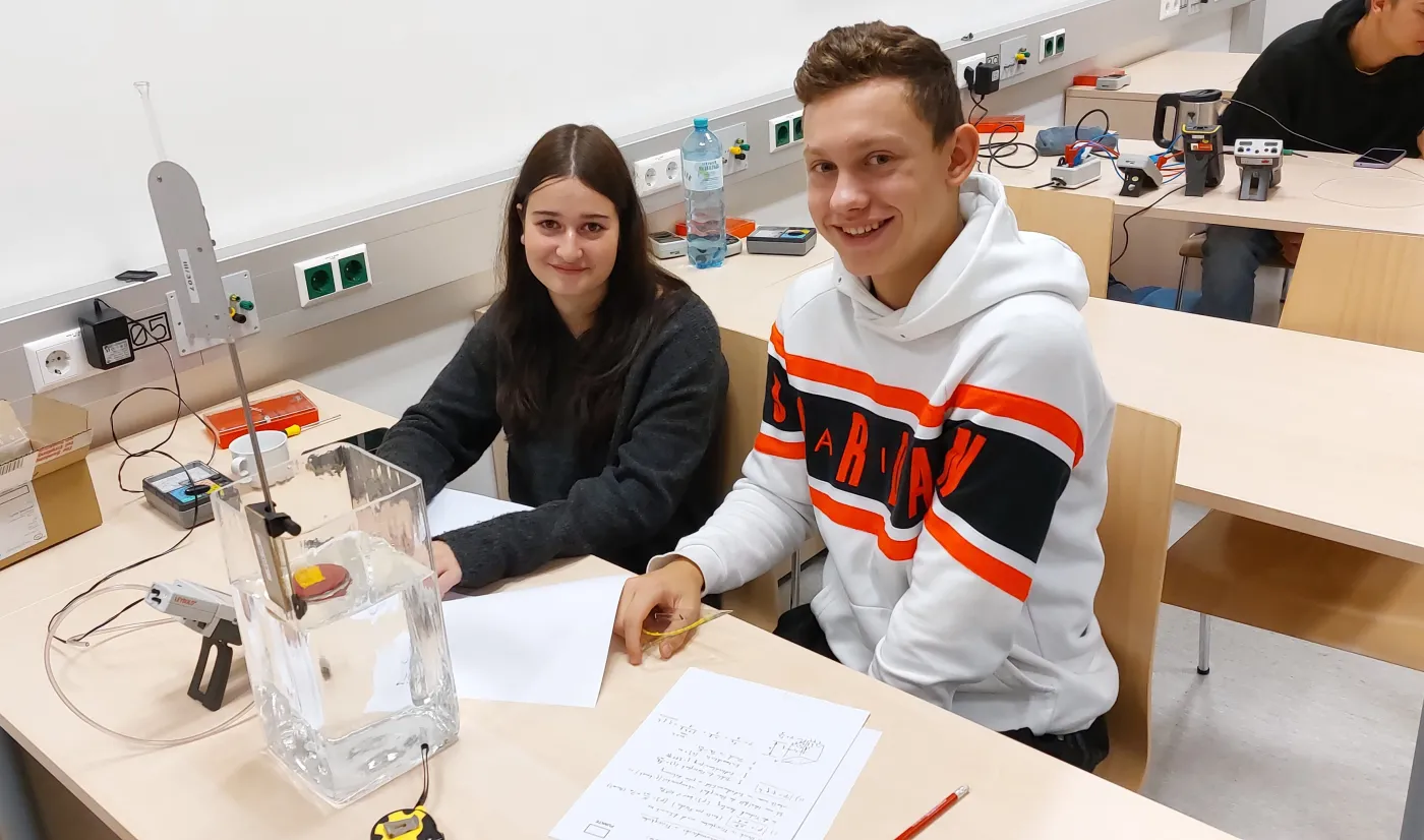 Zwei Sch&uuml;ler*innen bei einem Physikexperiment.