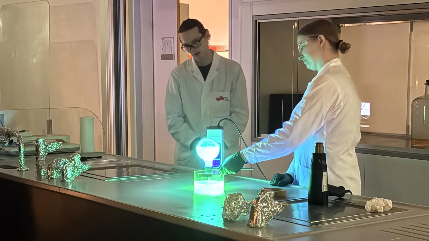 Chemie-Experiment: Gr&uuml;n leuchtende Substanzen in Kolben und Schalen.