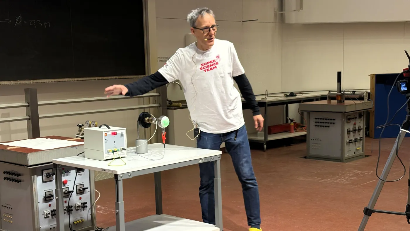 Der Professor zeigt ein Experiment mit einer Gl&uuml;hbirne.