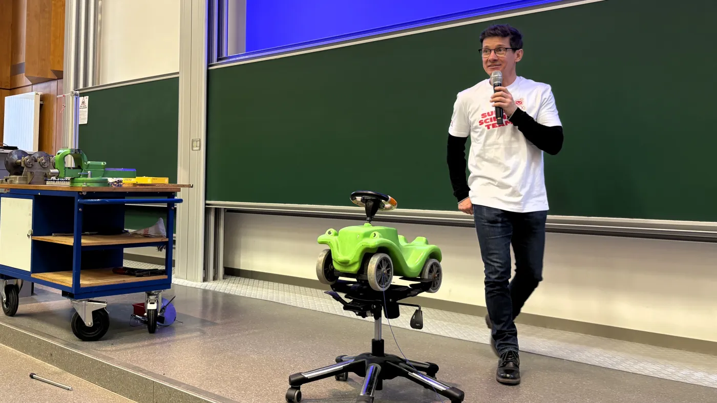 Ein Vortragender geht &uuml;ber die B&uuml;hne und h&auml;lt dabei das Mikrophon.