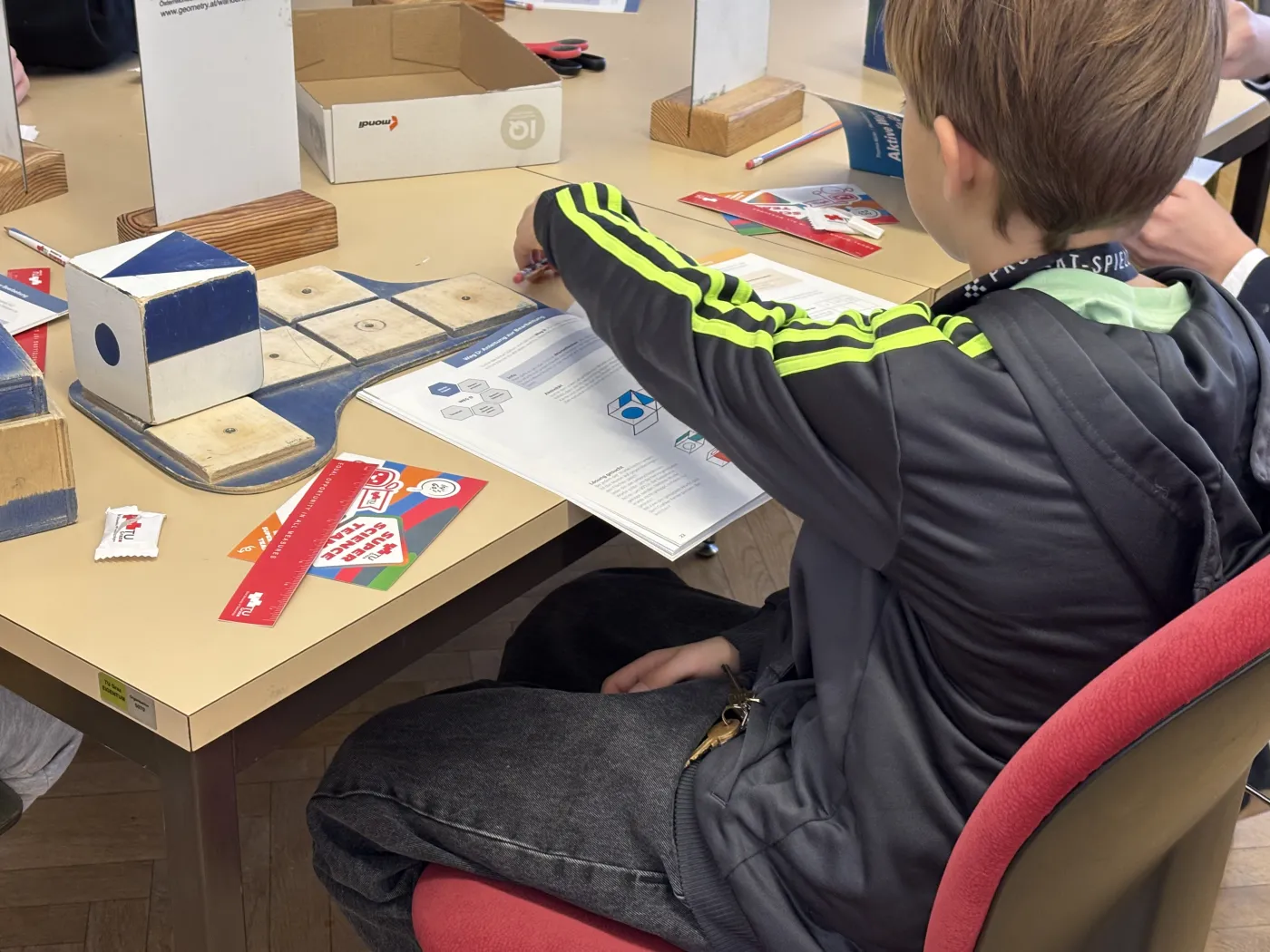 Ein Bub beim Geometrie Workshop. Man schaut ihm beim L&ouml;sen eines 3D-Puzzles &uuml;ber die Schulter.