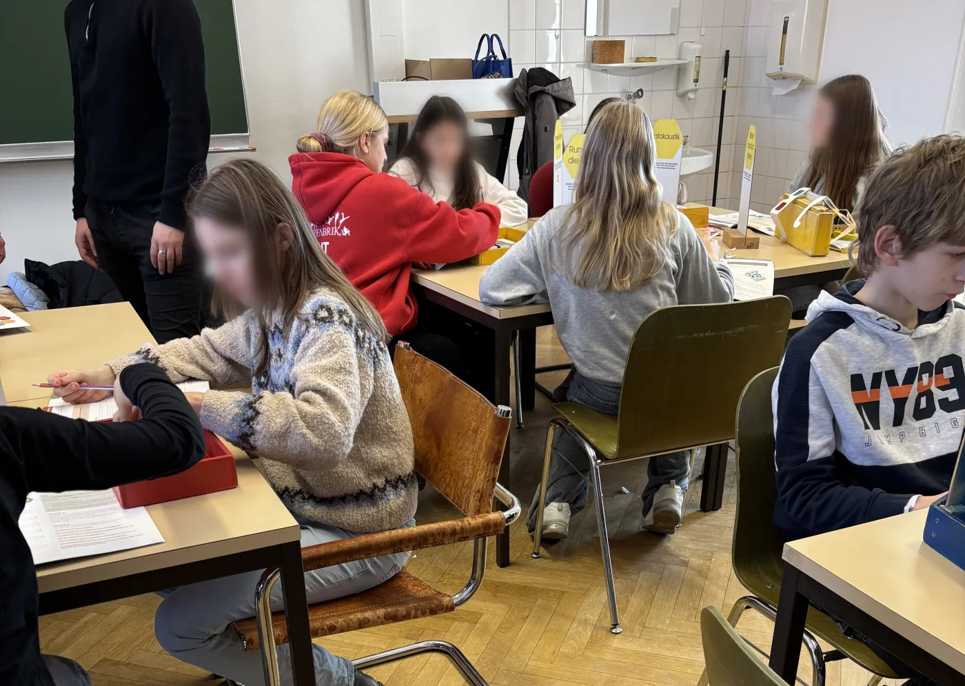 Die Sch&uuml;ler*innen sitzen an den Workshop-Tischen und arbeiten Eifrig an den Geometrieaufgaben.